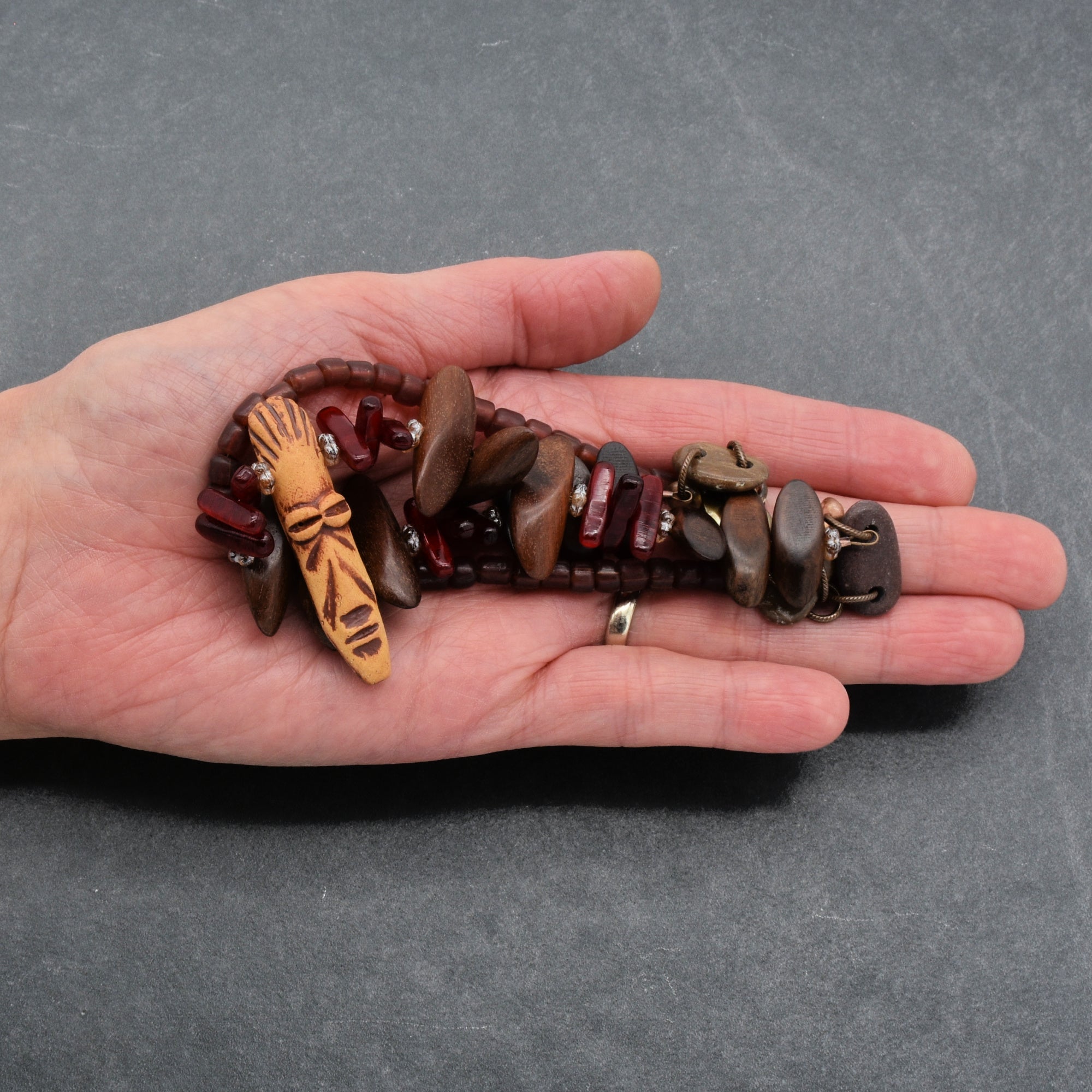 This piece of jewelry appears to be a bracelet. The length and the way it is being held in the hand suggest it is designed to wrap around a wrist. The presence of a clasp further confirms it as a bracelet rather than a necklace or earring.