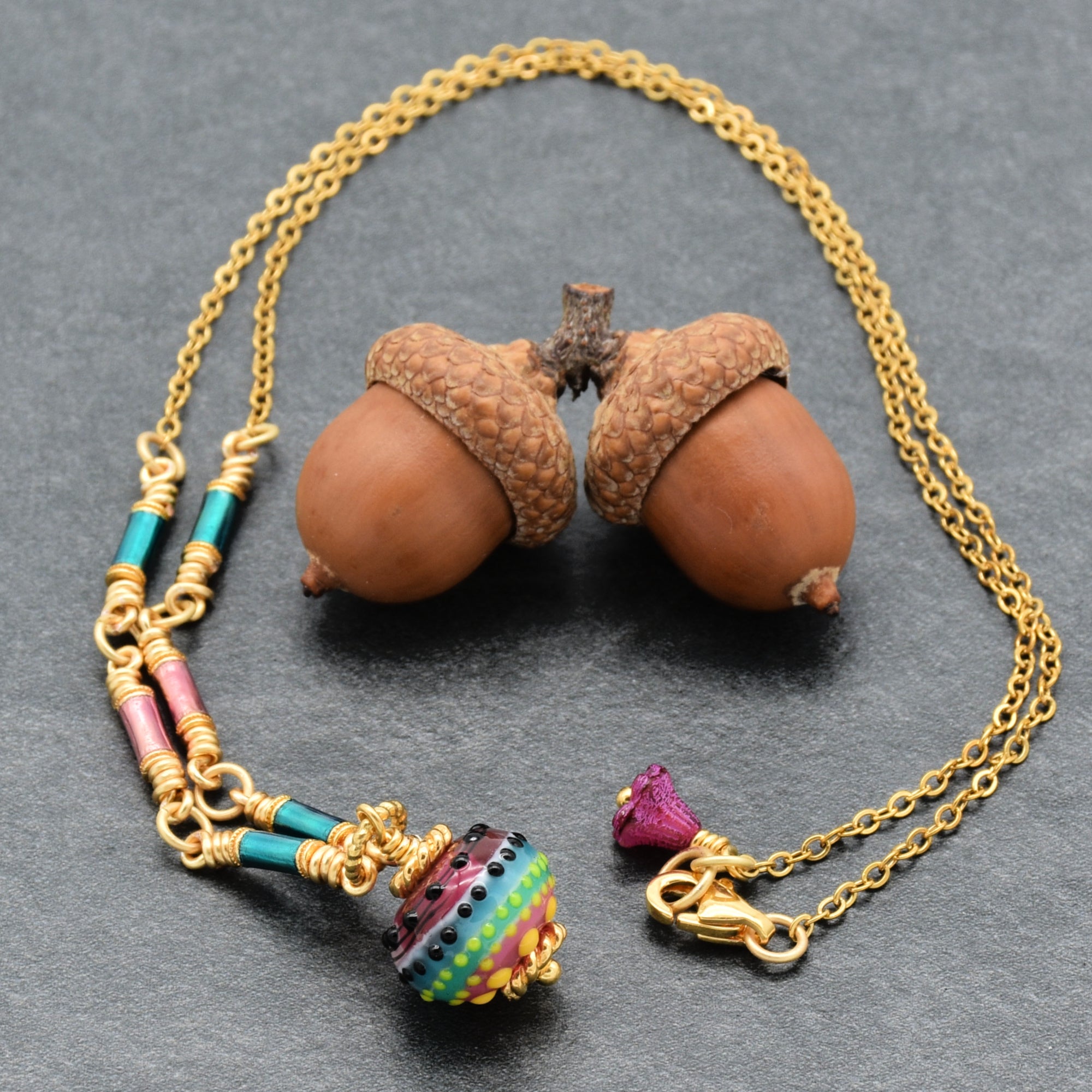 Gold chain necklace with colorful artisan lampwork glass focal and enamel tubes on a gray background - art you can wear by Ruby Acorn