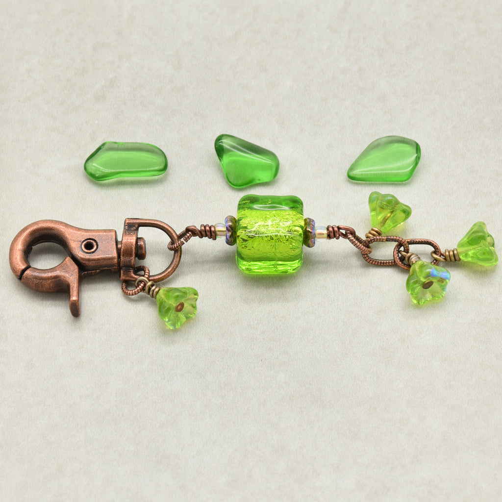 Green beaded keychain with a copper clasp on a light gray background