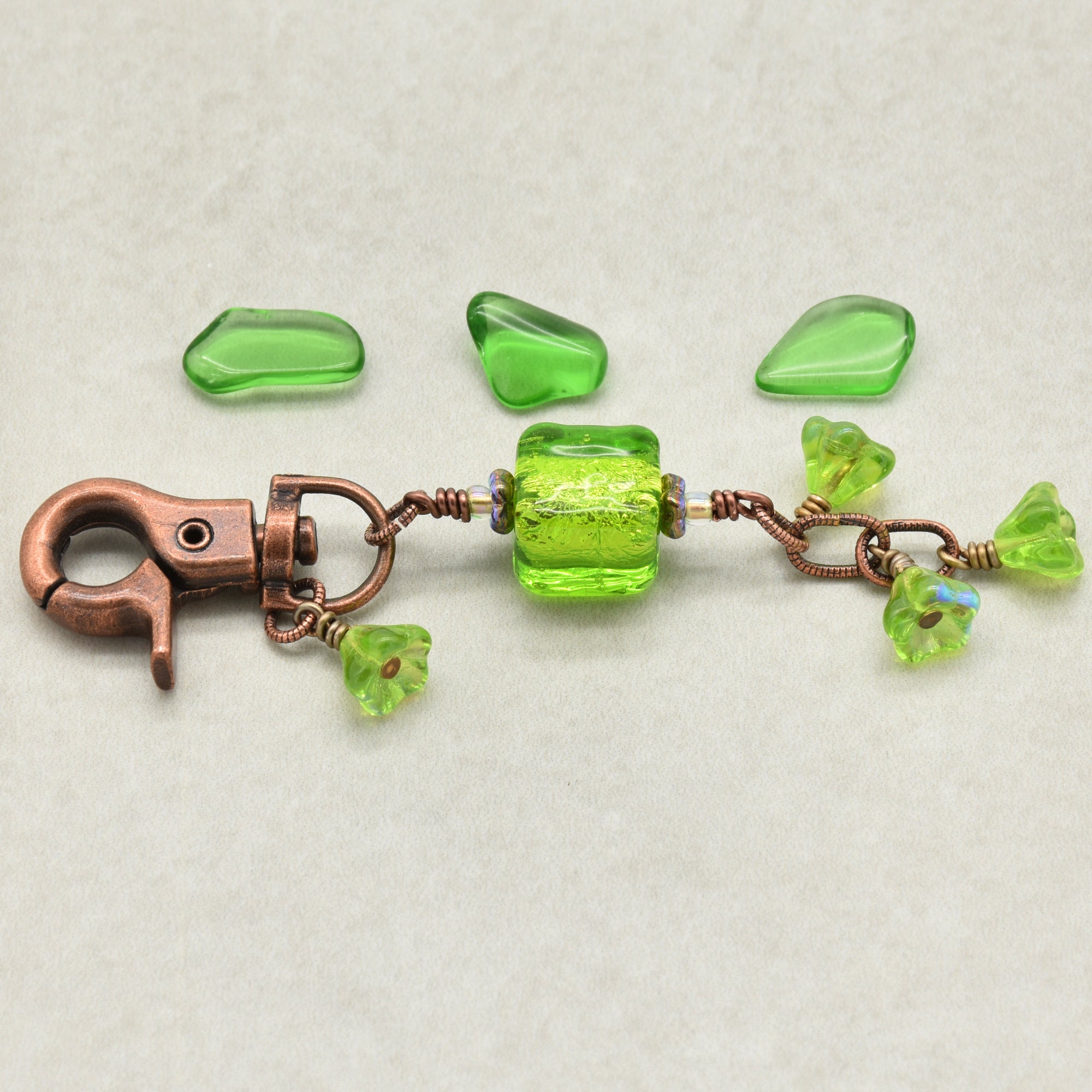 Green beaded keychain with a copper clasp on a light gray background