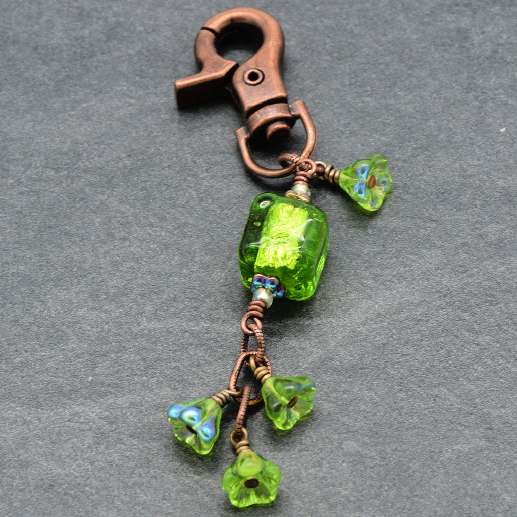 Green beaded keychain with copper clasp on a gray background