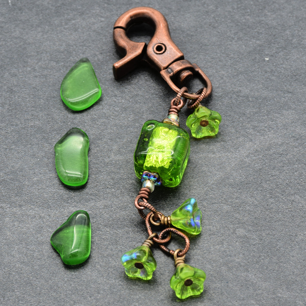 Green beaded keychain with a copper clasp on a gray background
