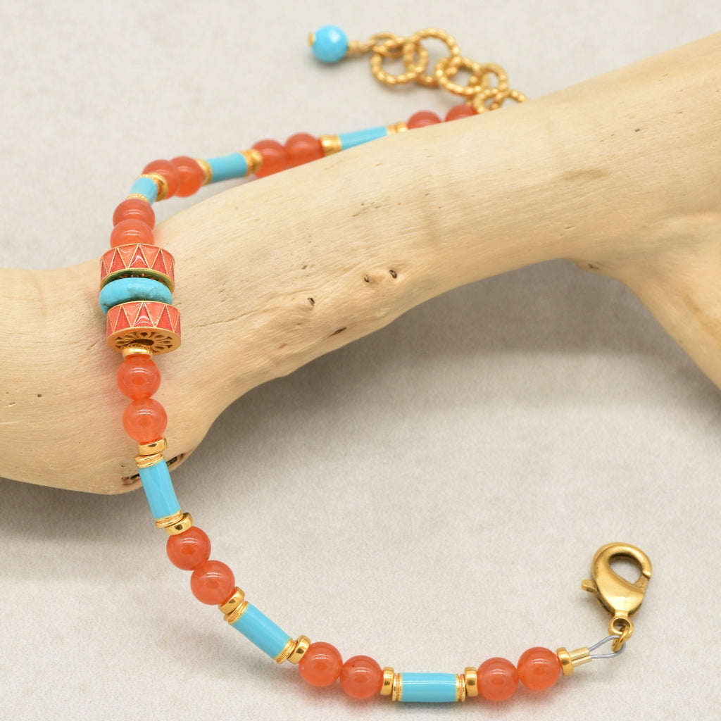 A beaded bracelet with coral-orange round beads, light blue turquoise cylindrical beads, and gold-toned spacer rings, displayed on a light wood branch against a neutral light gray background - made with love in Colorado by Ruby Acorn.