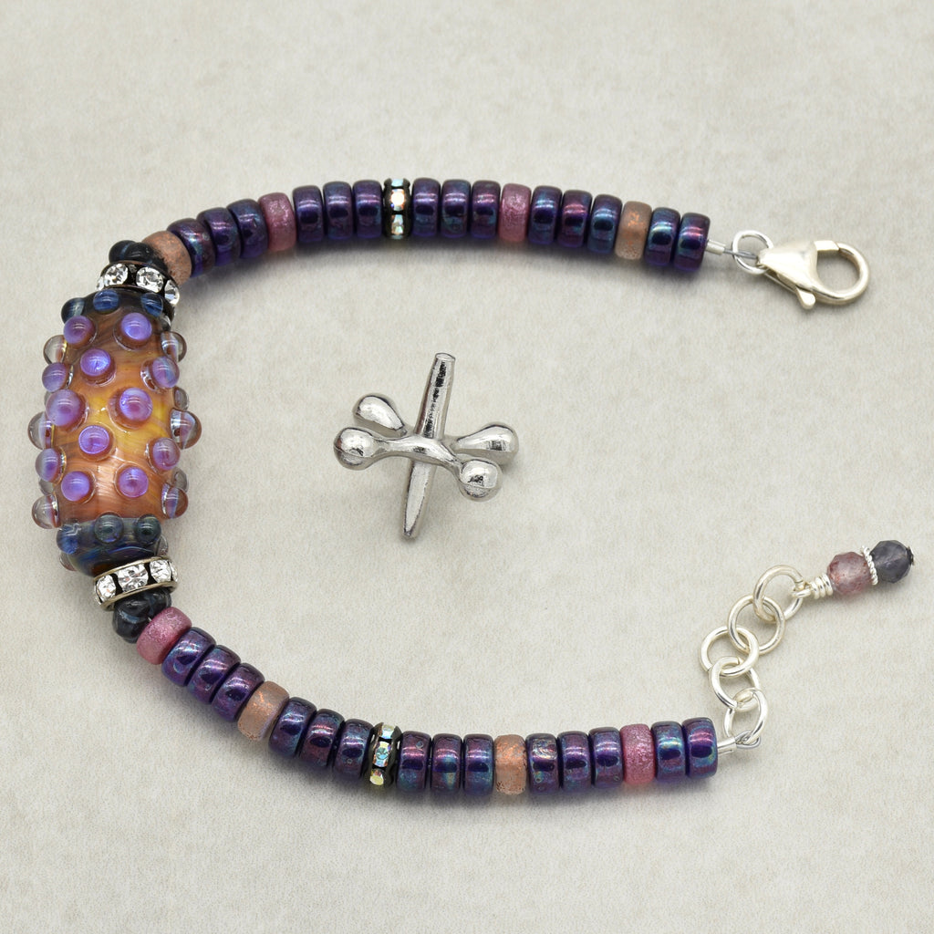 This image shows a bracelet. The jewelry piece has a clasp and an extension chain for adjusting the size, which are typical features of a bracelet. Additionally, the length and design with beads and a focal decorative bead suggest it is meant to be worn around the wrist.
