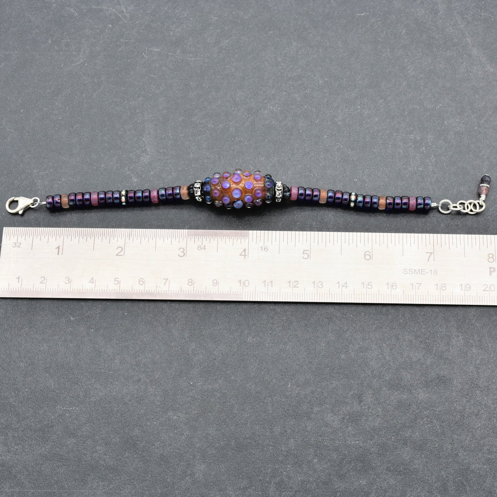 This image shows a bracelet. The size and shape, along with the clasp and length shown against the ruler, indicate it is designed to be worn around the wrist.