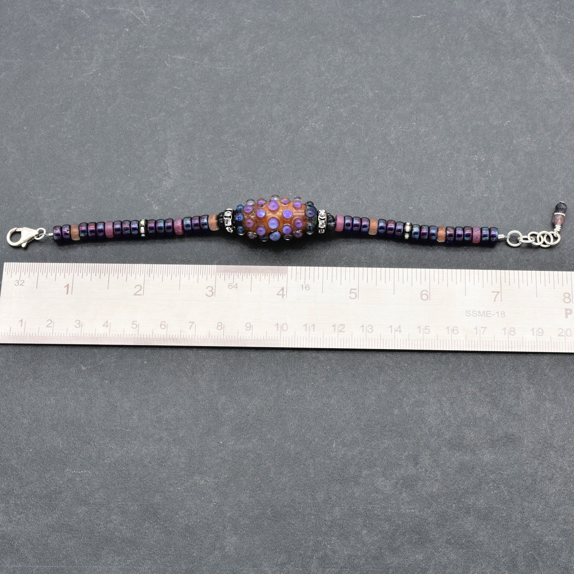 This image shows a bracelet. The size and shape, along with the clasp and length shown against the ruler, indicate it is designed to be worn around the wrist.
