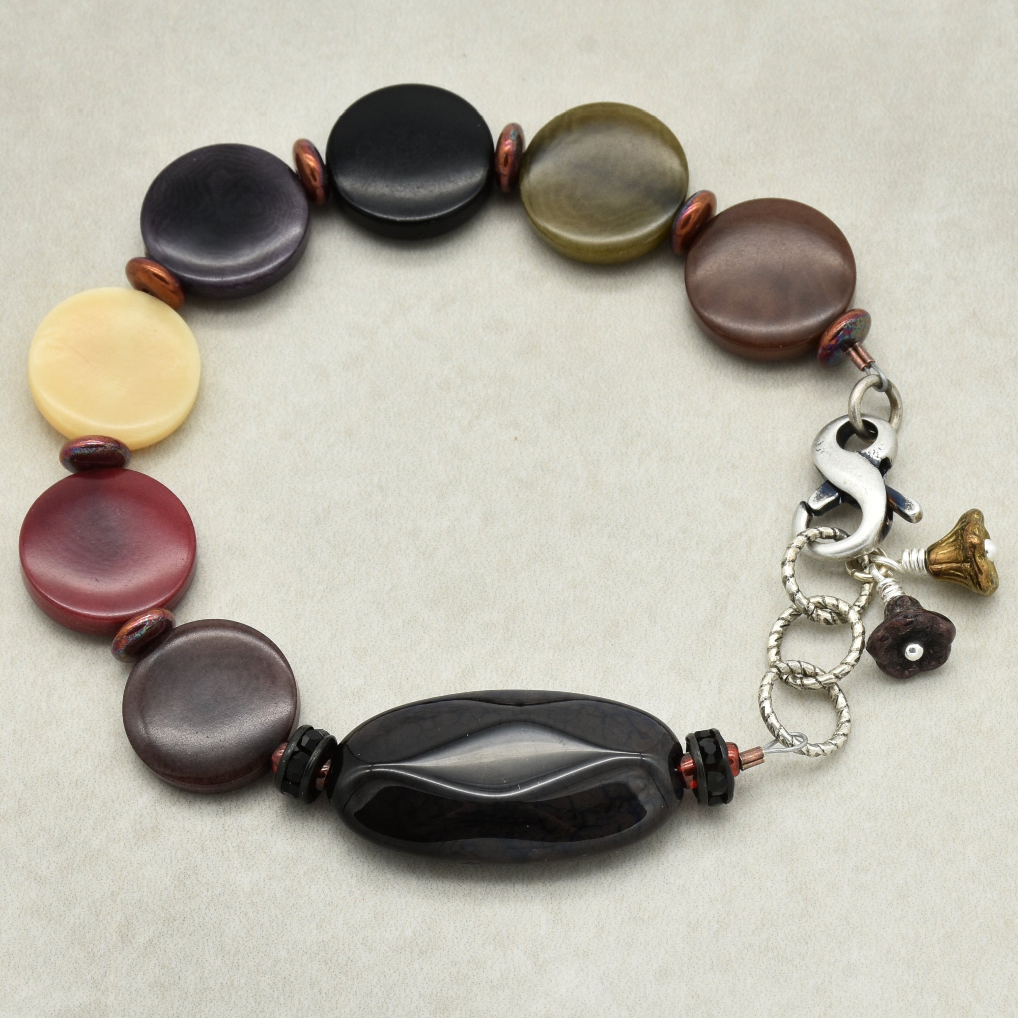 Multicolored beaded bracelet with a flower charms on a light gray background