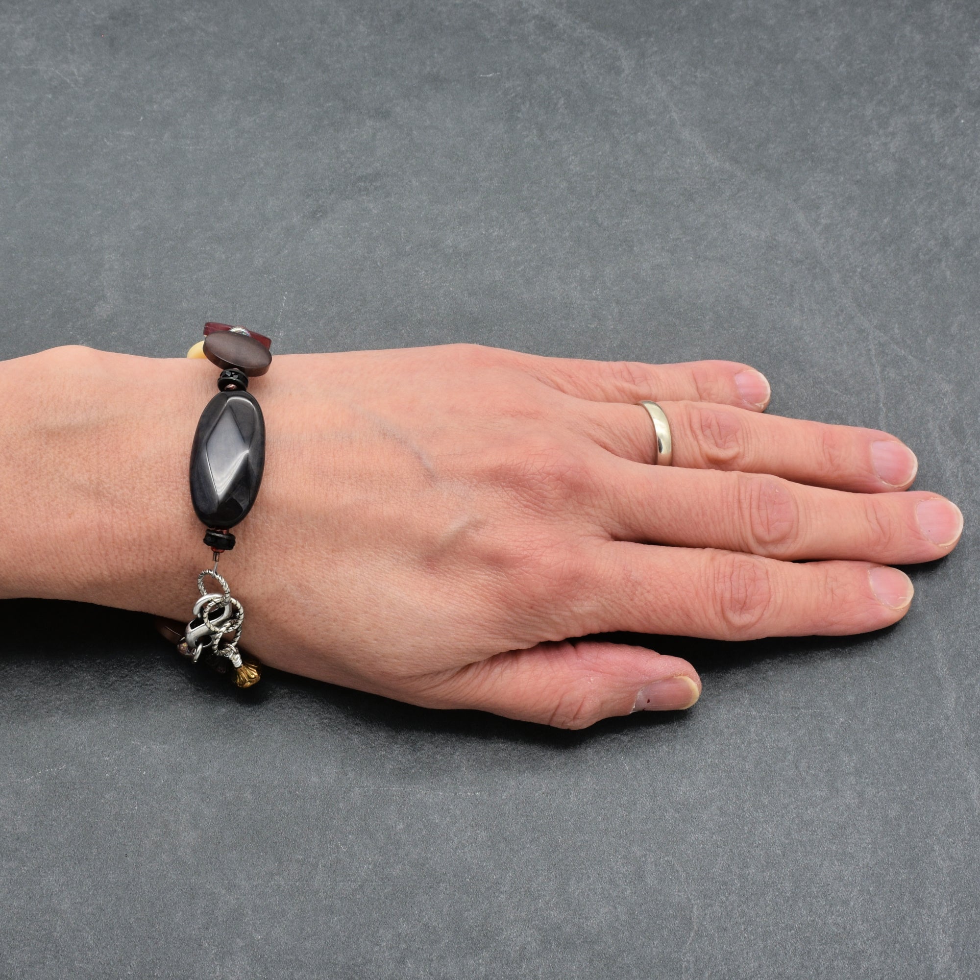 Hand wearing a bracelet on a gray background