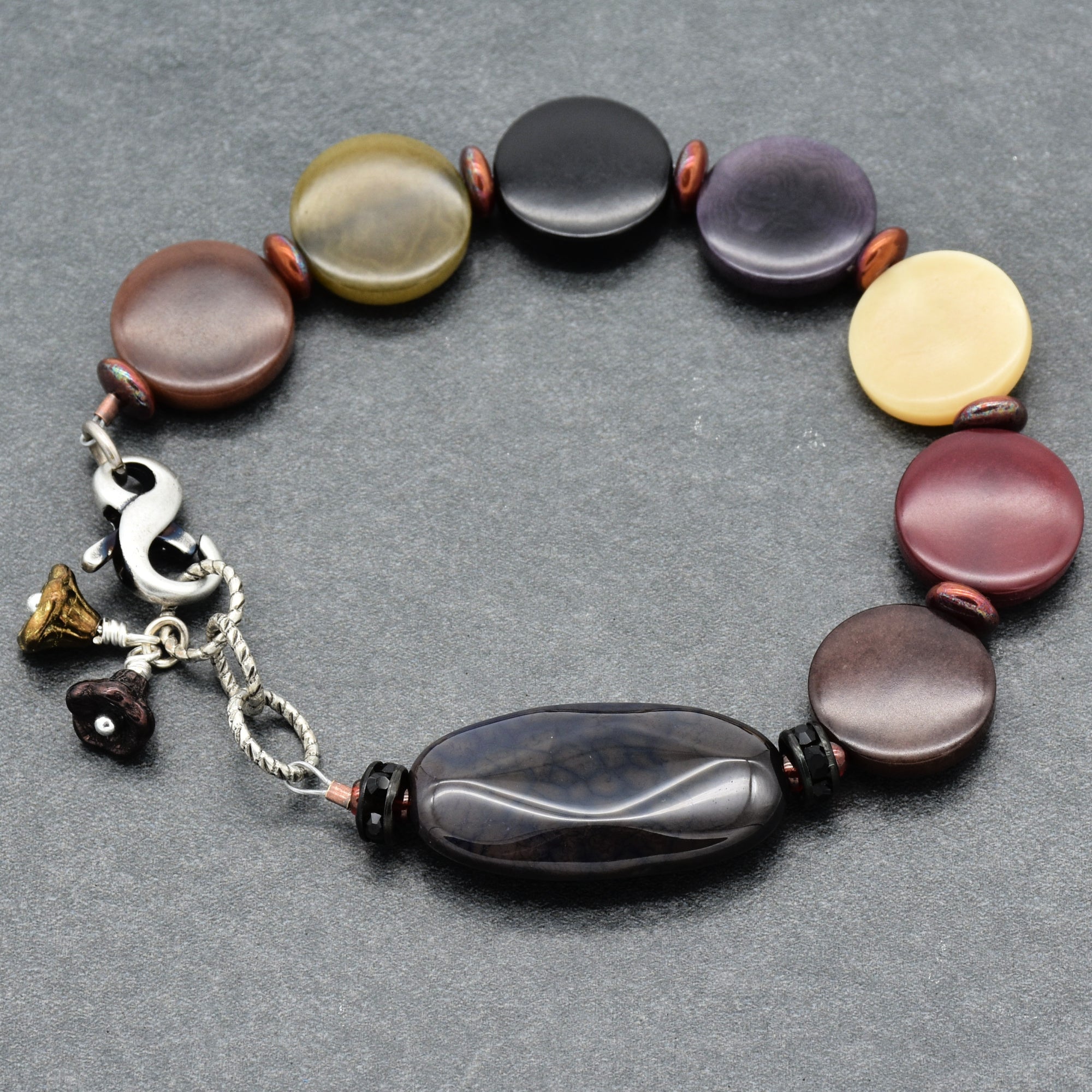 Multicolored beaded bracelet with flower charms on a gray background