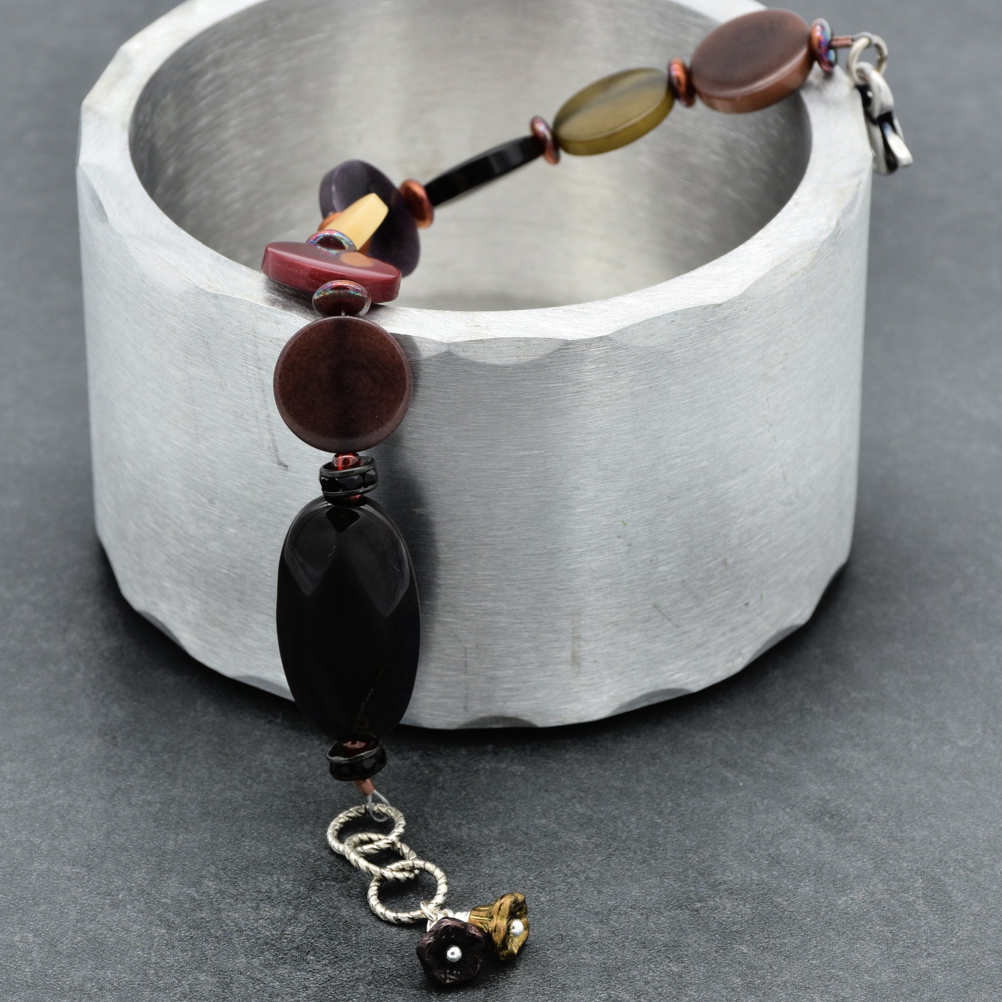 Beaded bracelet with brown and black beads on a metallic surface