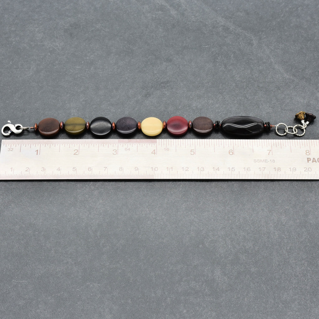 Bracelet with multicolored beads on a gray surface with a ruler for scale.