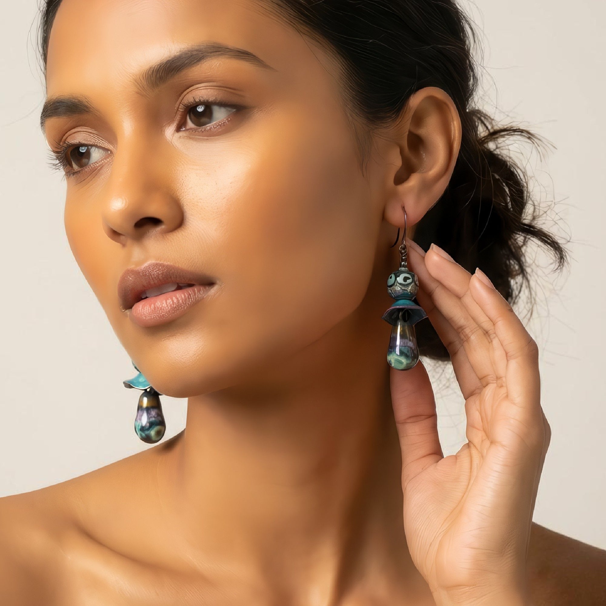 Woman wearing a pair of earrings with a neutral background