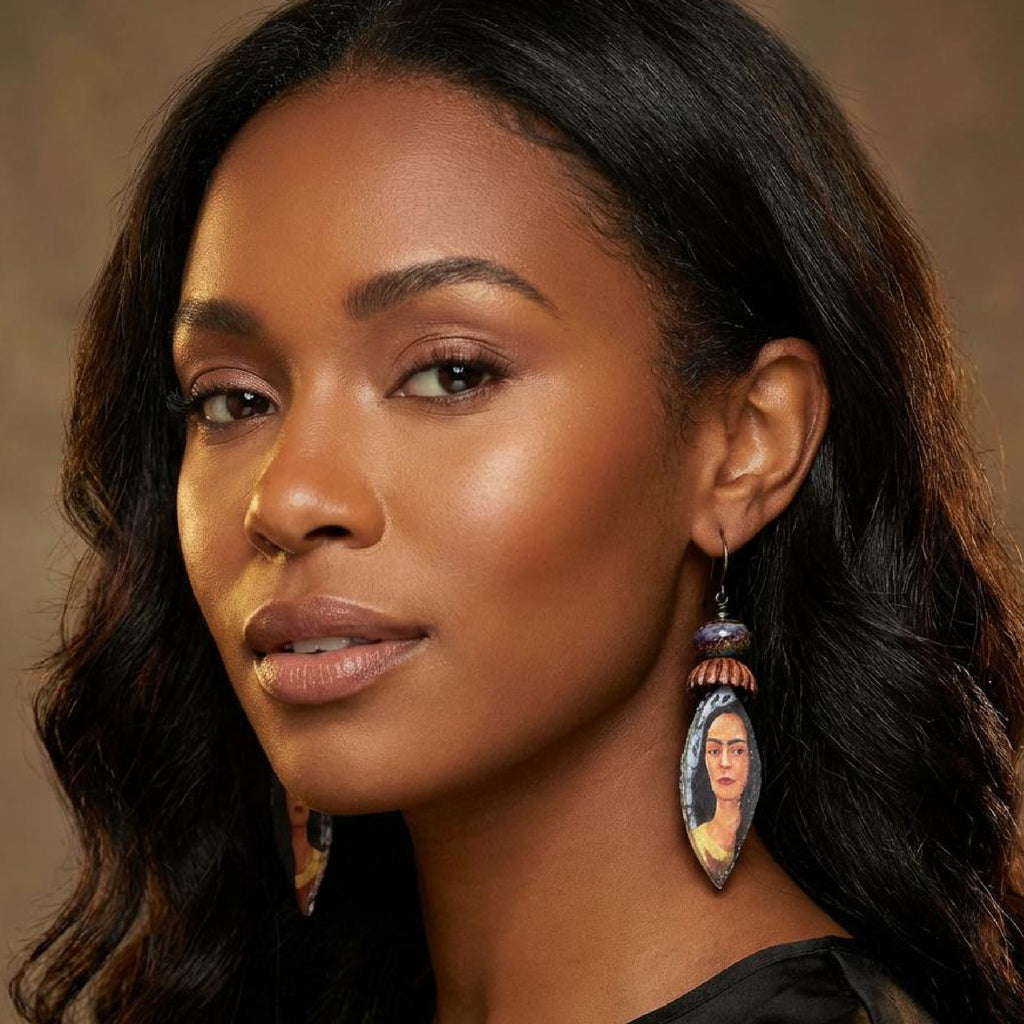 Woman wearing earrings with a portrait design against a neutral background