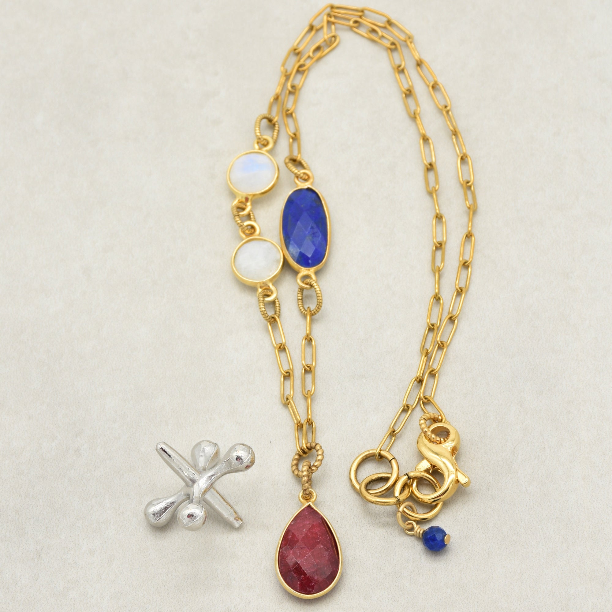 Close up of a delicate gold chain necklace with ruby pendant and lapis and rainbow moonstone links - one of a kind wearable art by Ruby Acorn