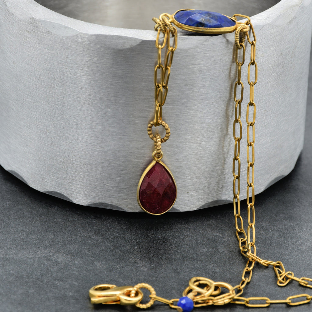 Close up of a delicate gold chain choker necklace with a ruby pendant, lapis link and an infinity lobster claw - art that tells your story by Ruby Acorn