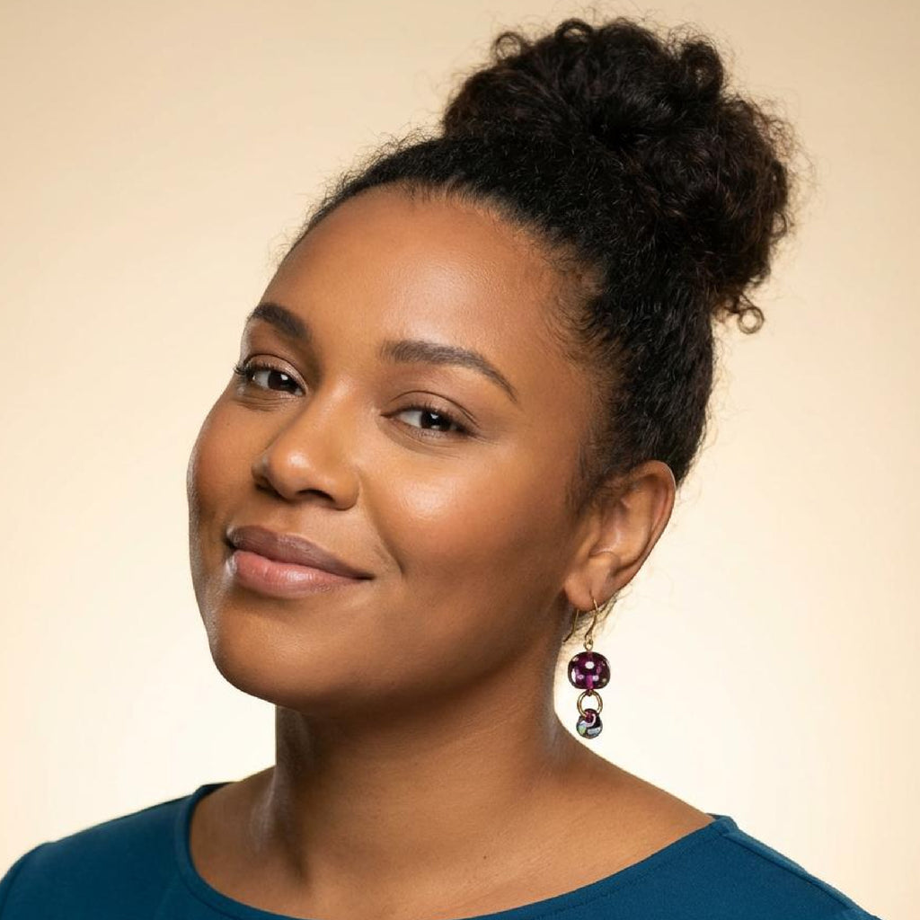 Woman with styled hair and earrings against a beige background