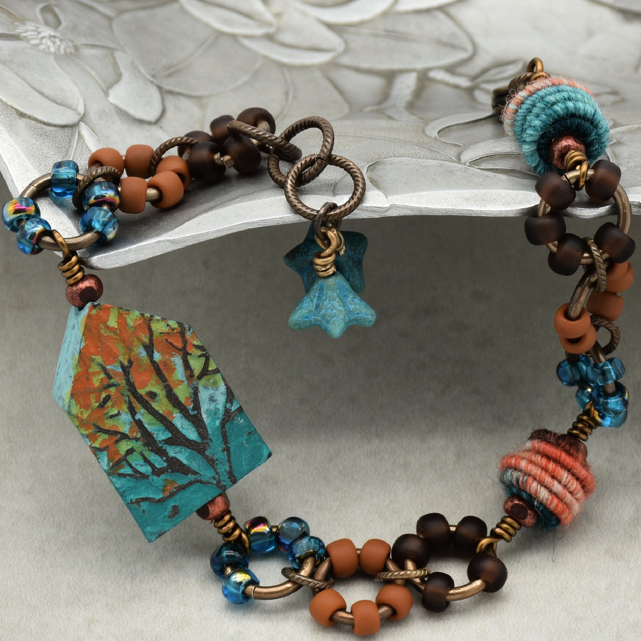 Colorful beaded bracelet with decorative elements on a textured surface - Ruby Acorn original art