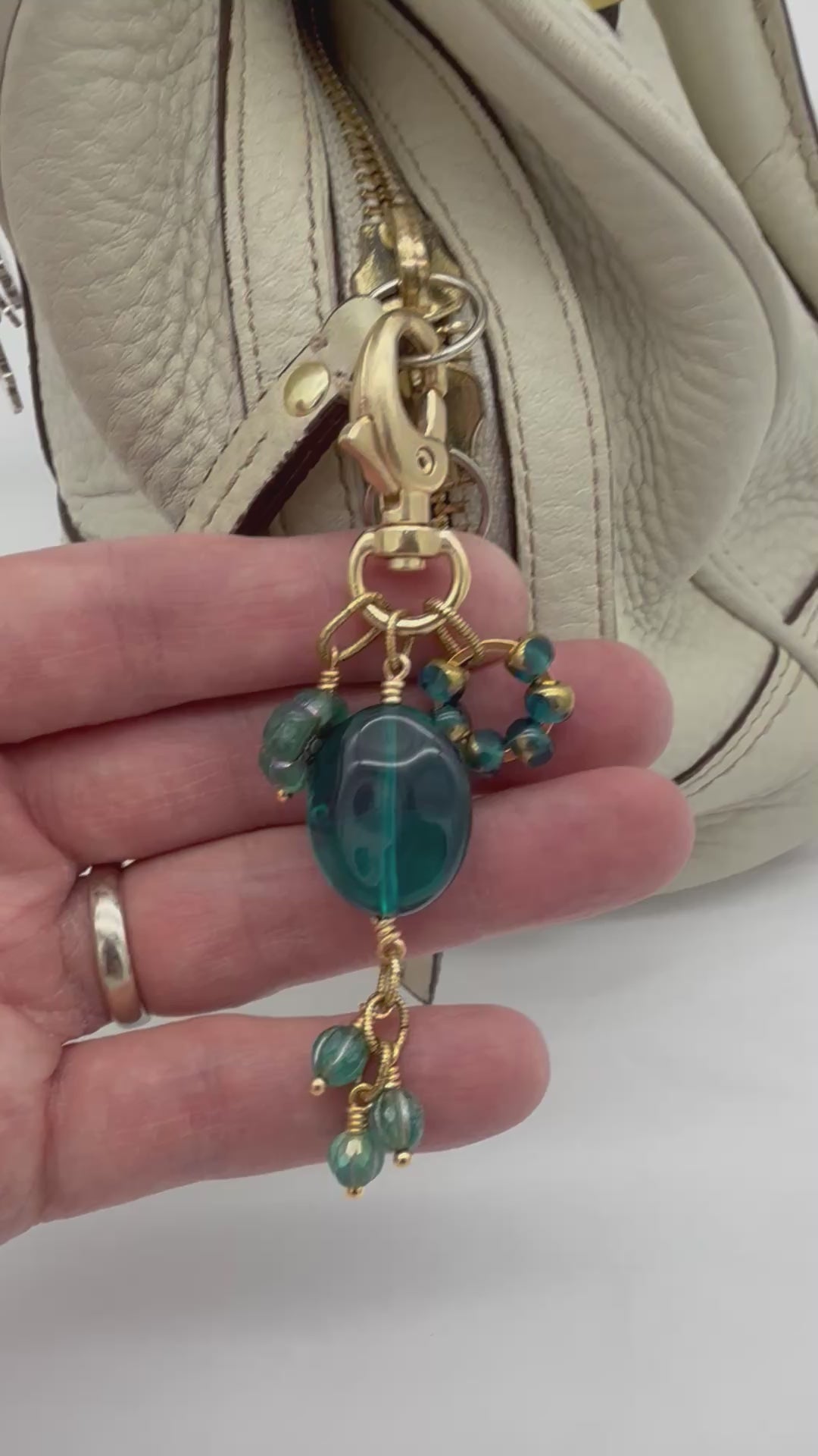 Video of Aqua Blue handbag charm with gold swivel lobster claw on a cream purse - handmade with love by Ruby Acorn