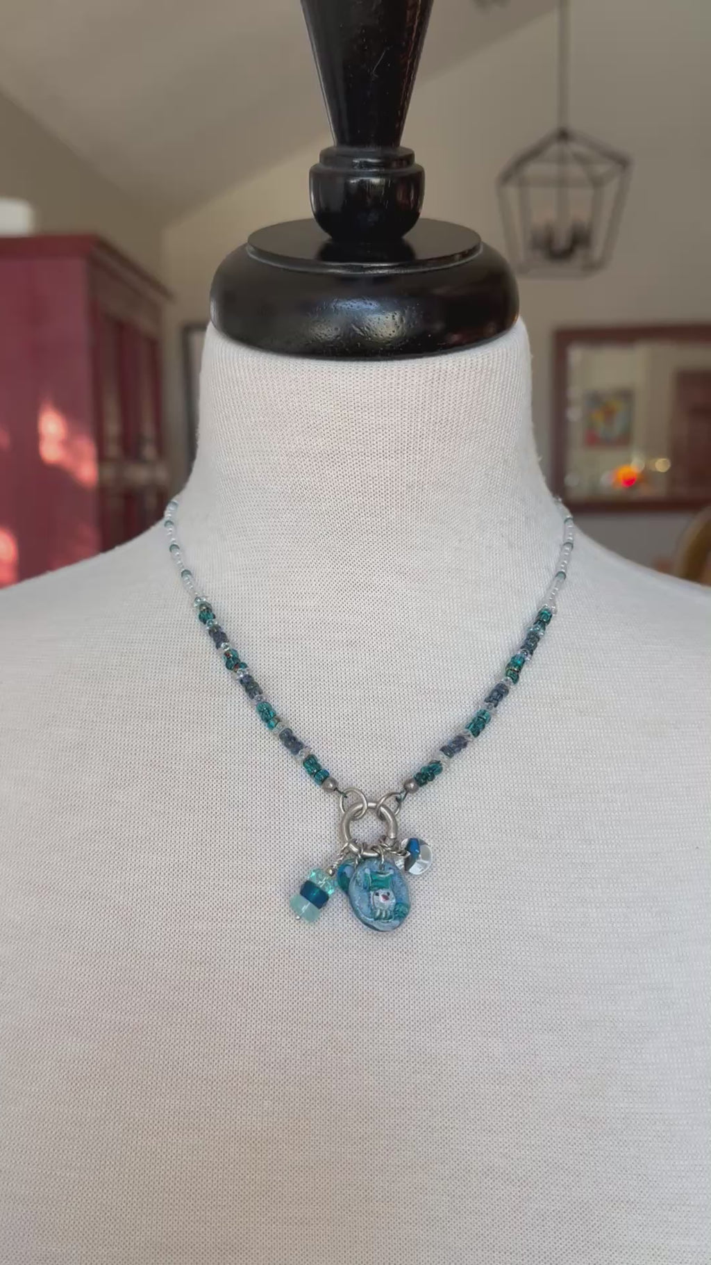 Video of festive blue charm necklace on a mannequin