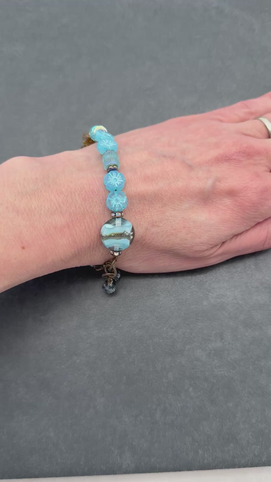 Video of hand wearing a light blue hand crafted beaded bracelet. 