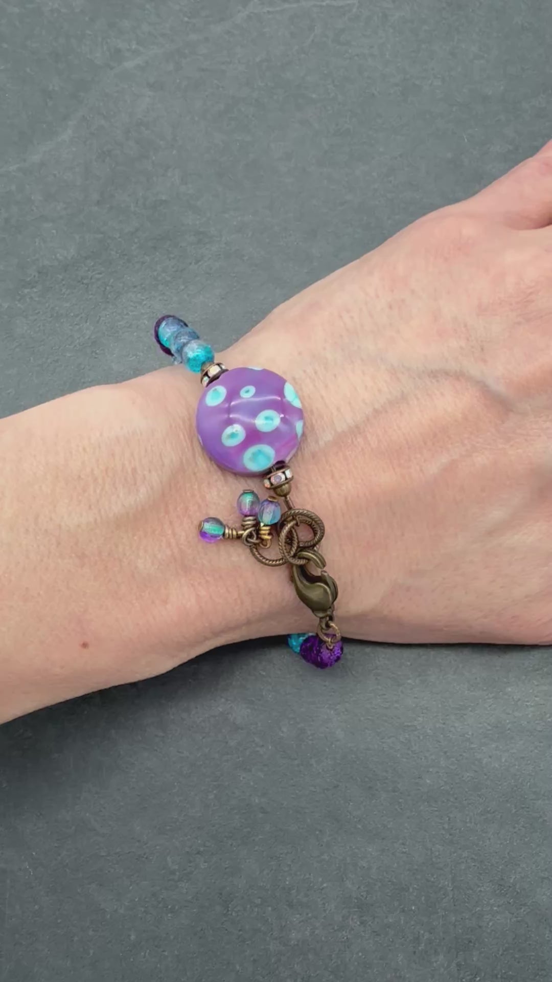 Video of hand wearing beaded bracelet with purple and blue beads.