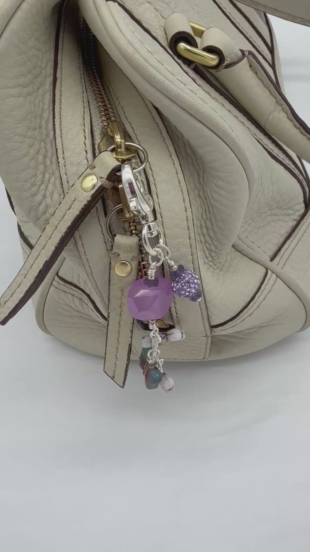 Video of a lilac quartz handbag charm with butterfly charms on a cream purse - handmade with love by Ruby Acorn
