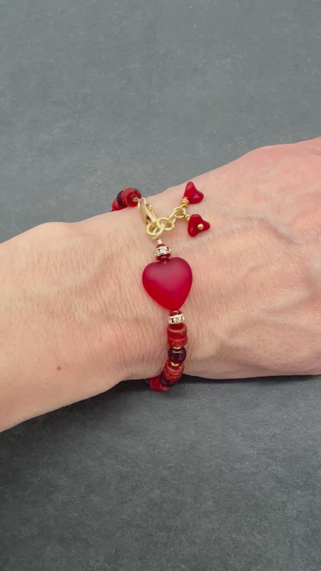 Video of hand wearing heart beaded bracelet with gold accents.