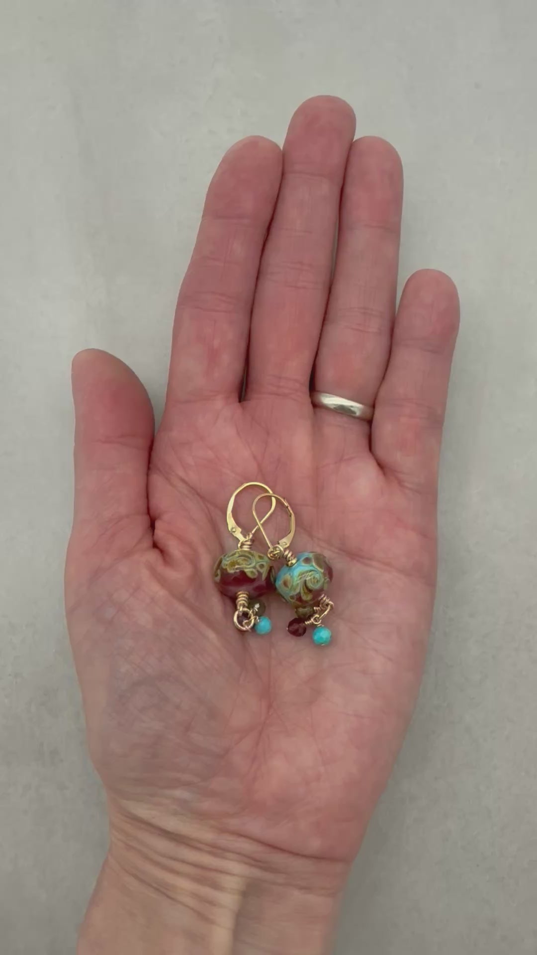 Video of hand holding colorful dangle earrings