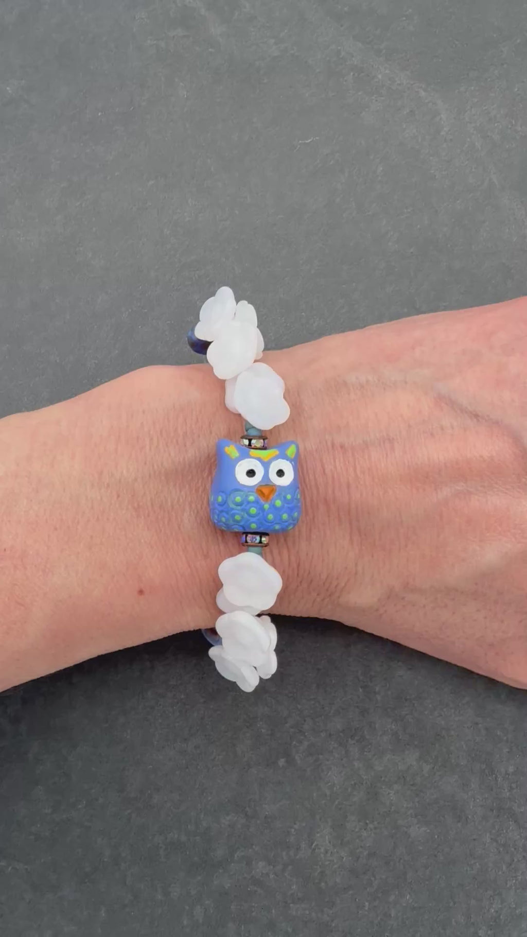 video of hand wearing floral bracelet with owl focal