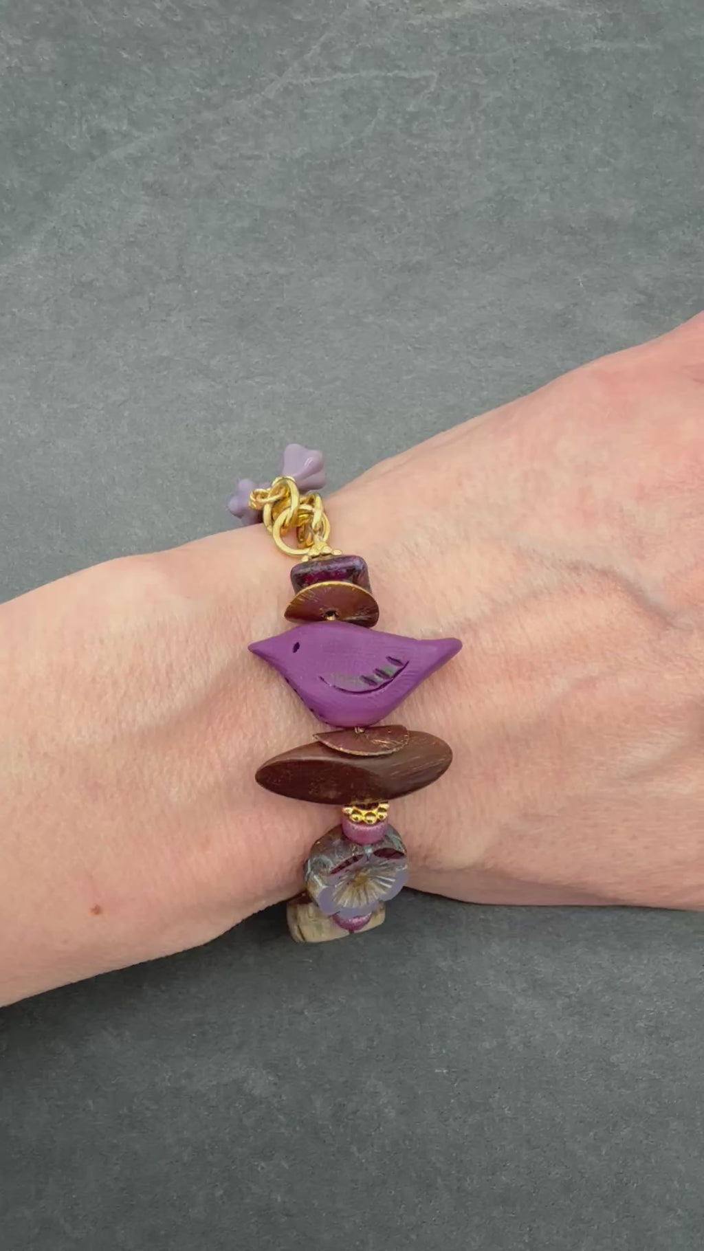 Video of hand wearing beaded bracelet with bird focal
