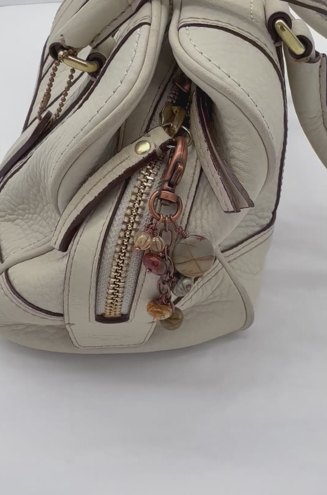 Video of a handbag charm with a copper lobster claw, red creek jasper stones, and Czech glass charms, displayed on a cream purse - made with love in Colorado by Ruby Acorn.