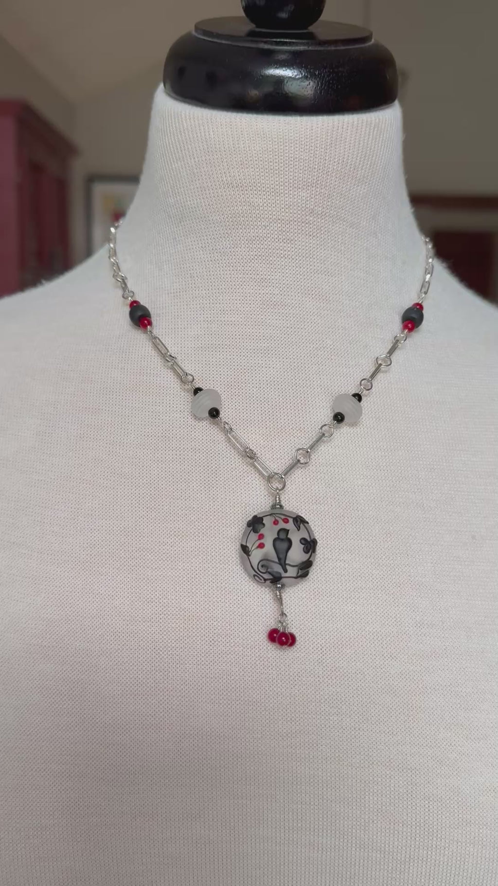 Video of a sterling silver necklace with a lampwork glass pendant with a black raven display on a mannequin - made with love in Colorado by Ruby Acorn.