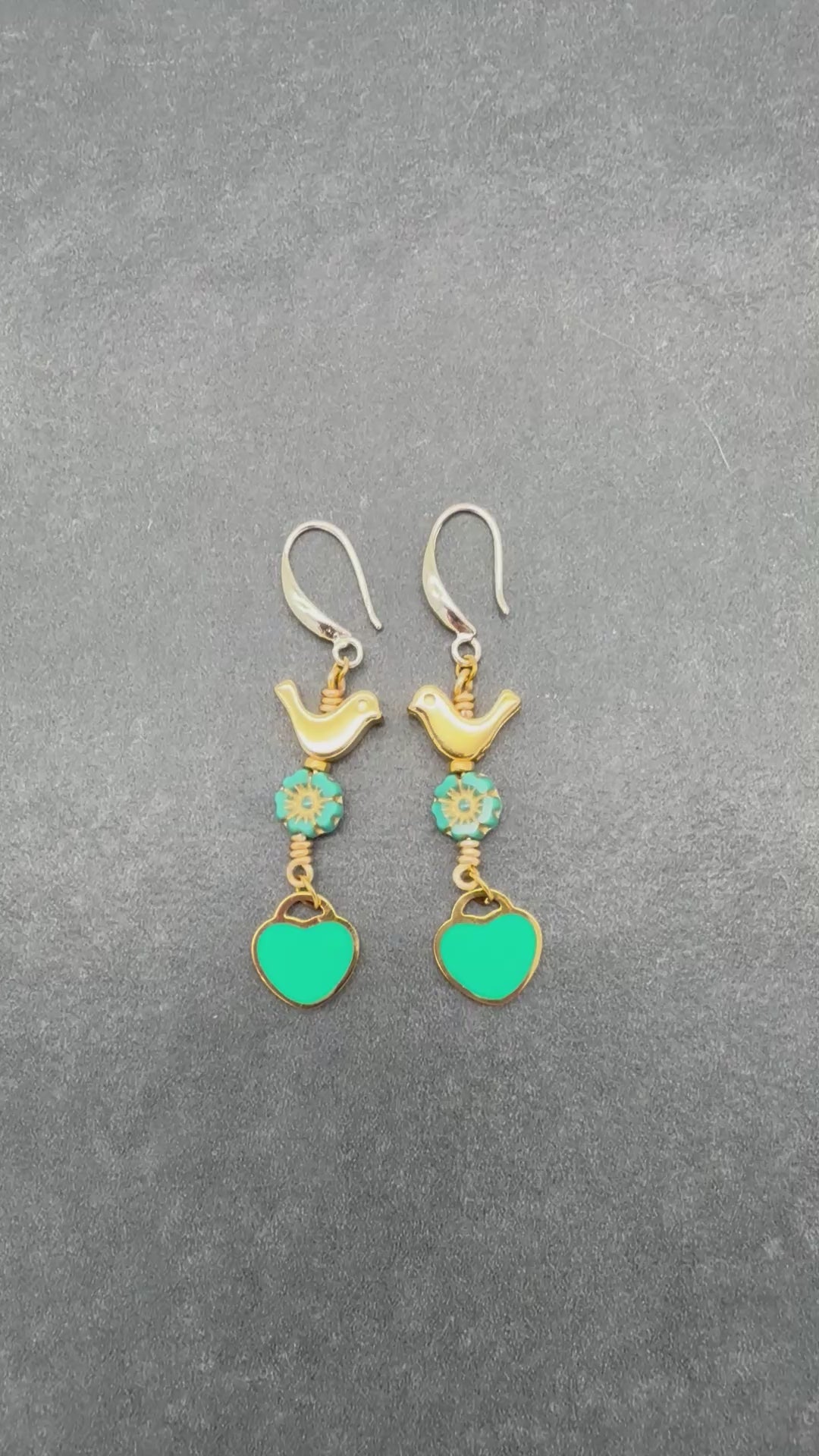 Video of Lovebirds Turquoise Blue dangle earrings with gold birds and heart charms on a gray background - handmade with love by Ruby Acorn
