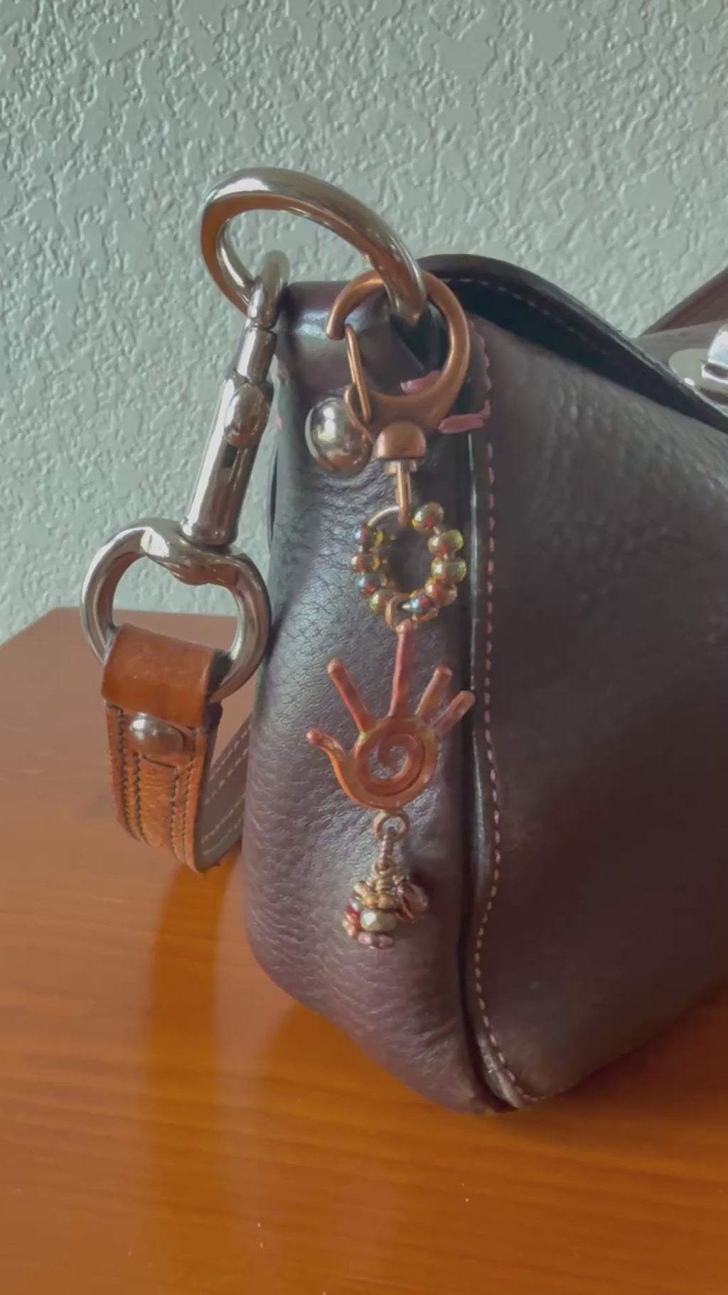 Video of brown leather purse with decorative copper handbag charm