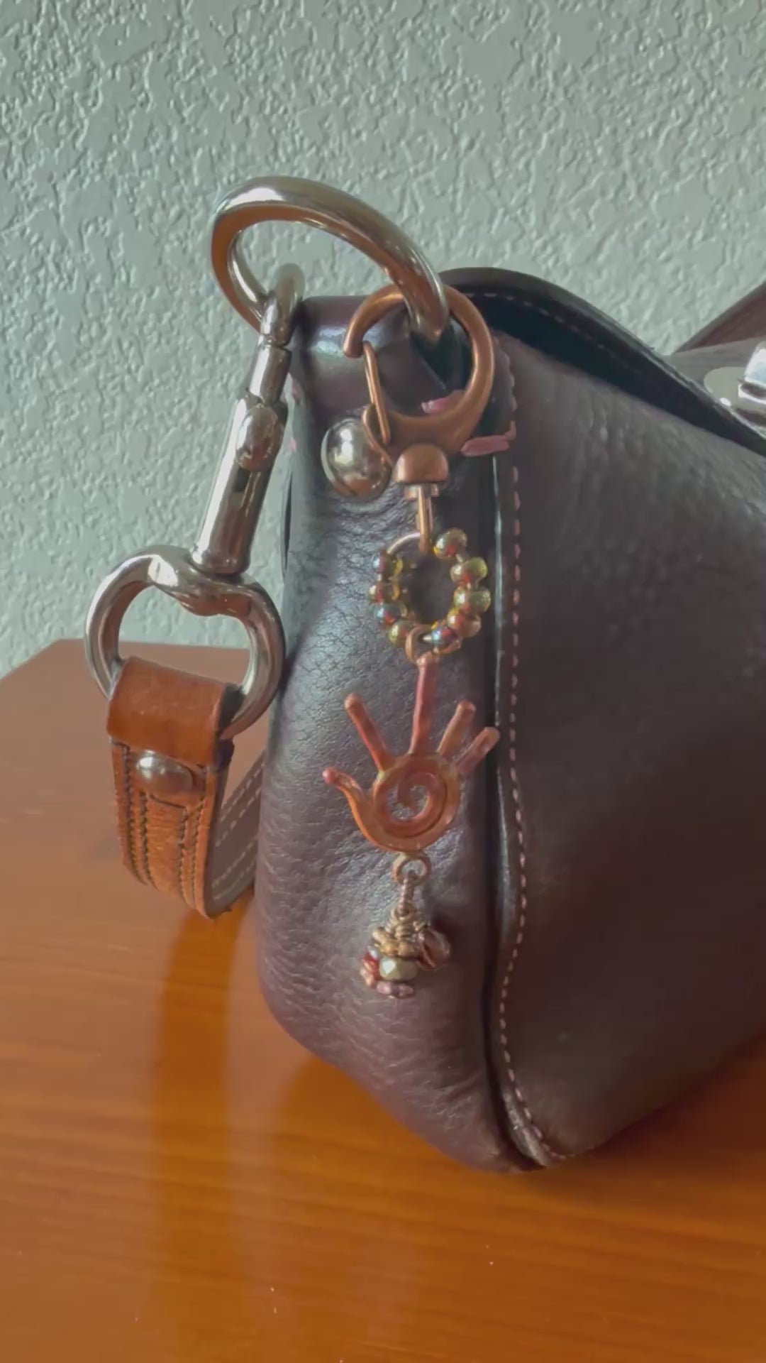 Video of brown leather purse with decorative copper handbag charm