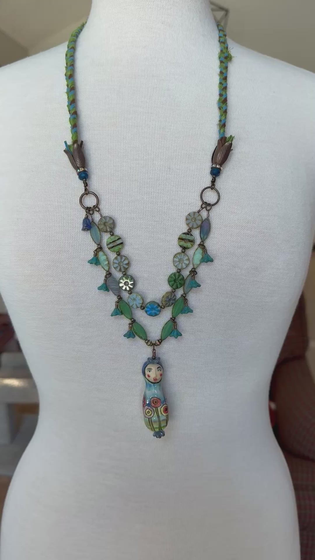 Video of long statement necklace with Russian Doll focal on a mannequin
