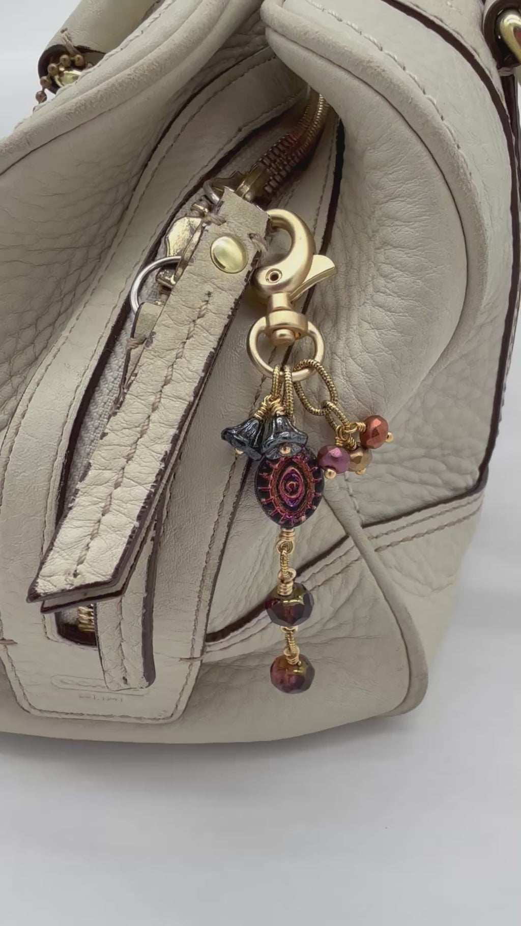 Video of Ember Eye Handbag Charm featuring a graphite gray Czech glass evil eye focal with shimmery copper center, handmade by Ruby Acorn