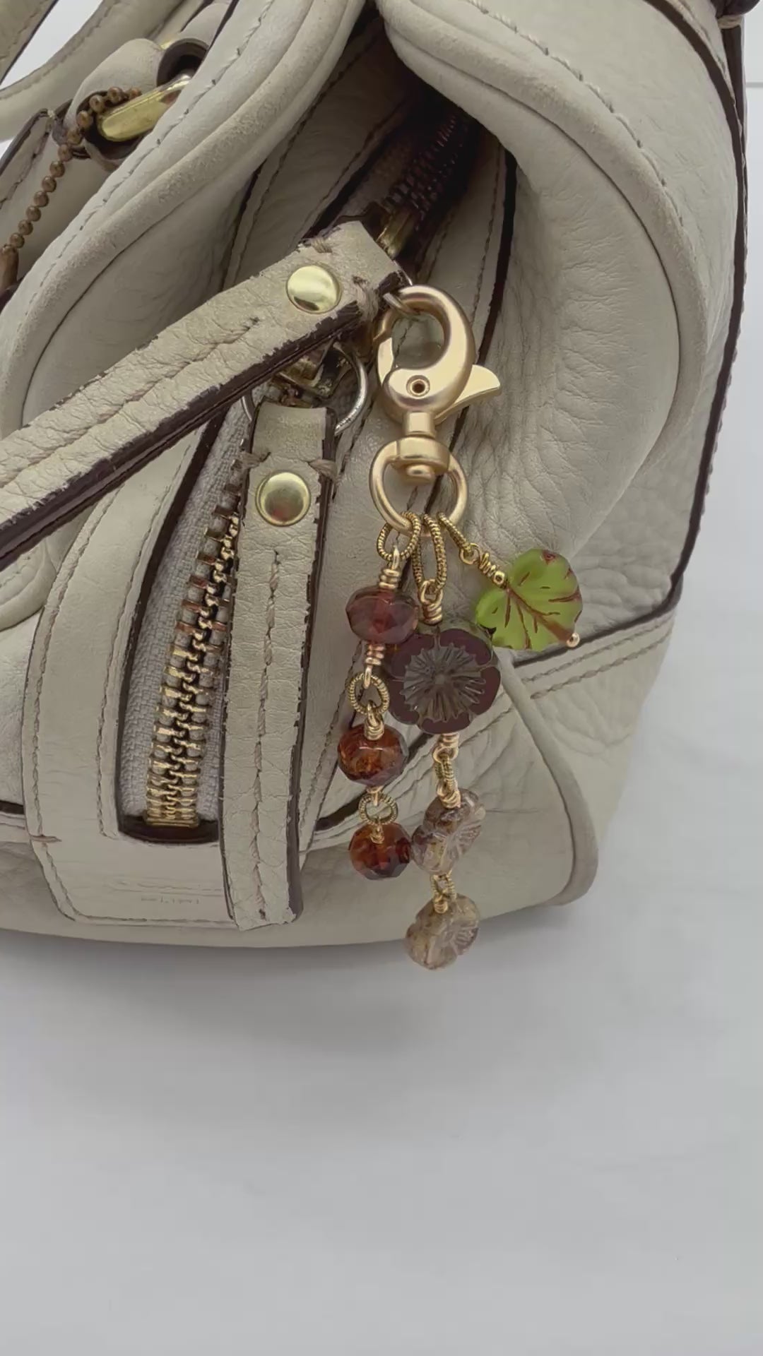 Video of Harvest Bloom Handbag Charm featuring wire-wrapped rust hibiscus flowers and olive green maple leaf charm, handmade by Ruby Acorn