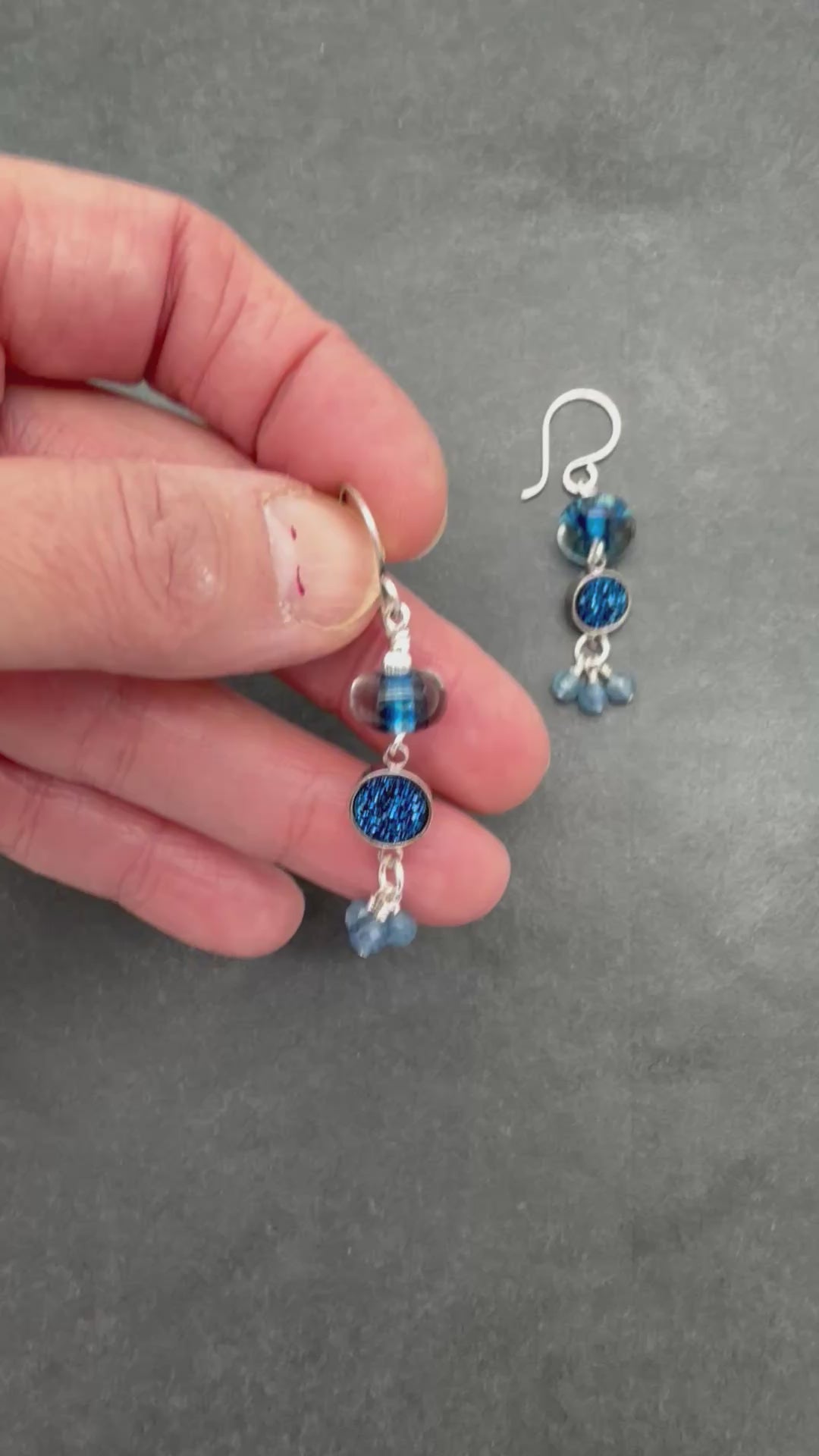 Video of hand holding blue beaded earrings with silver hooks